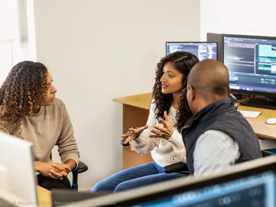 University employees sitting down and workstation and talking