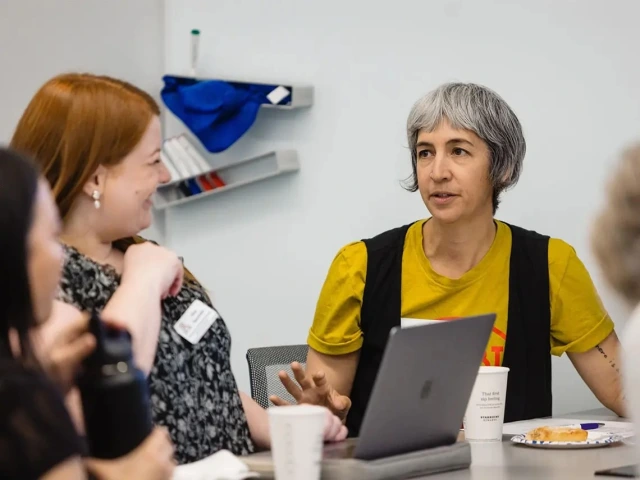 Two people talking in front of a laptop