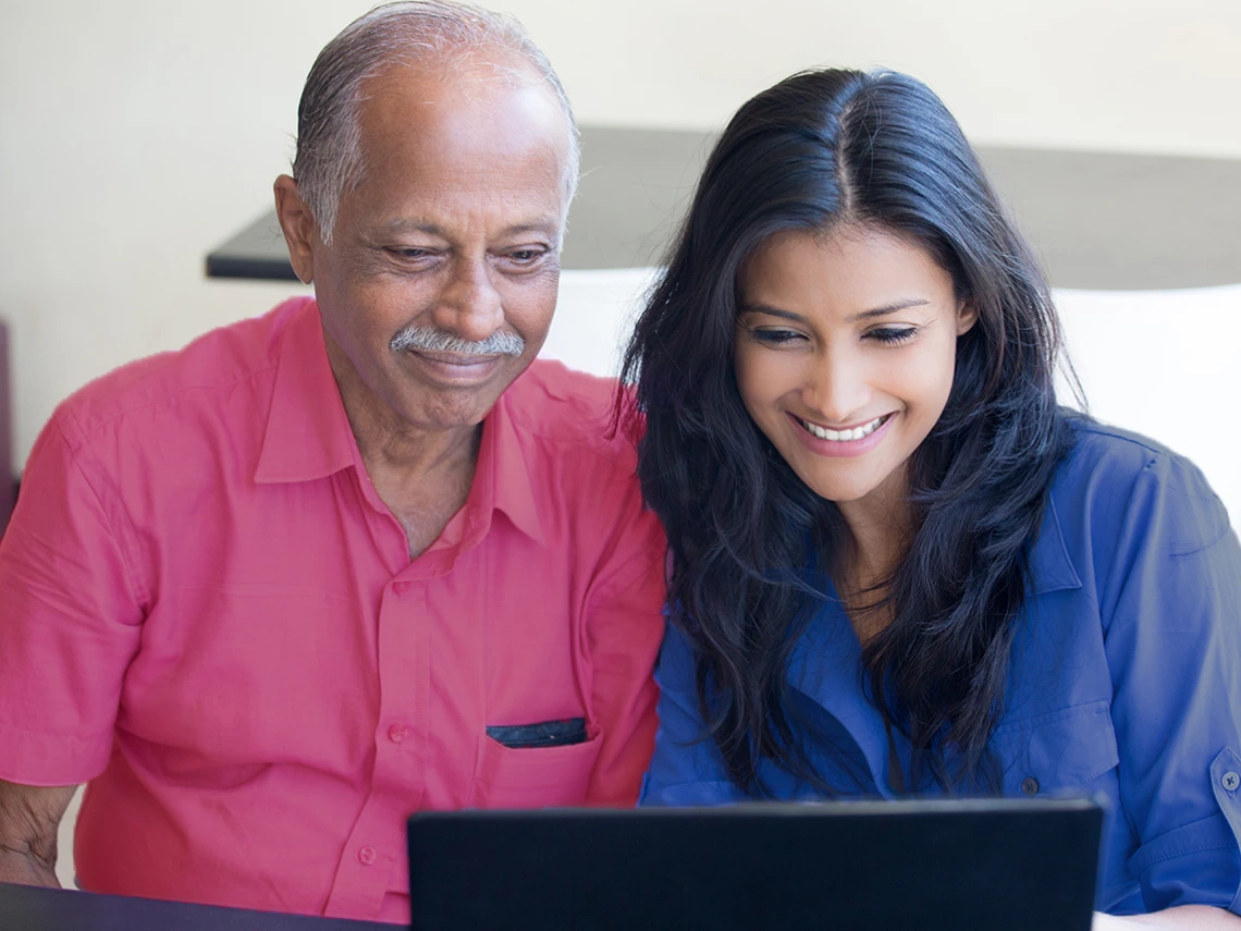 A Latina student and her father work together on a laptop