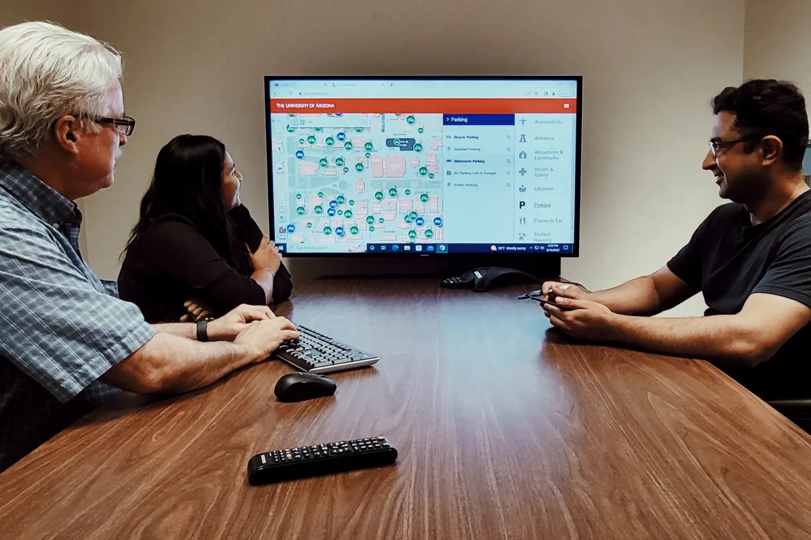 The EGIS team sitting around a table and looking at a map on a large monitor.