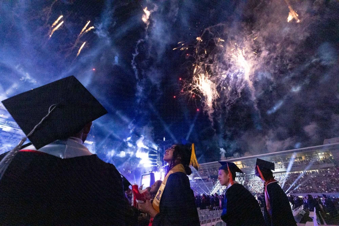 Students at Graduation with Fireworks overhead.