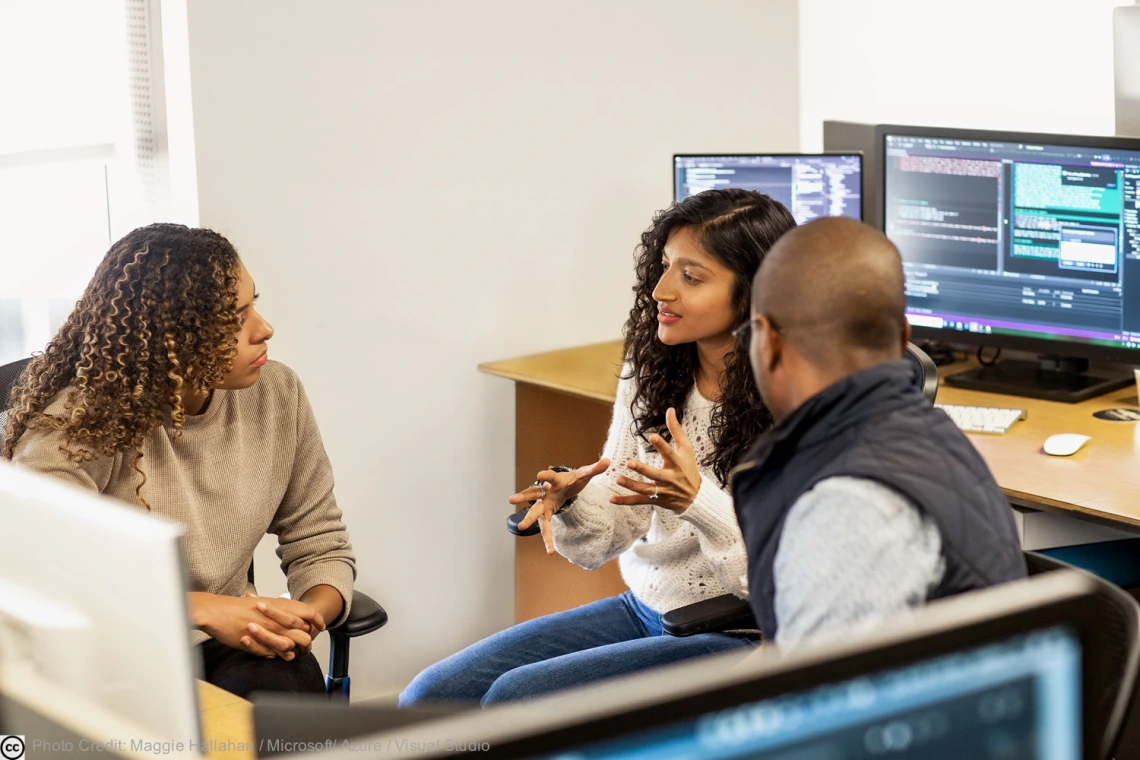 University employees sitting down and workstation and talking