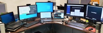 desk with 7 computers arrayed in an arc