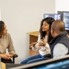 University employees sitting down and workstation and talking