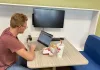 A student lunches while he works on his computer in the SUMC Tech Zone Lounge